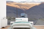 Behang - Fotobehang Vrachtwagen tussen de bergen - Breedte 600 cm x hoogte 400 cm