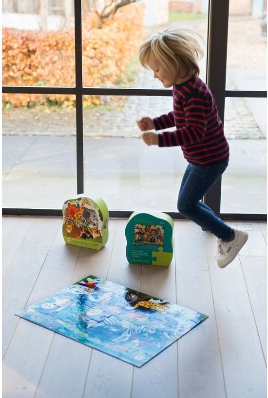 Een jongen springt vrolijk in de lucht naast twee jungle friends vloerpuzzels en een uitgestalde puzzel op de vloer.