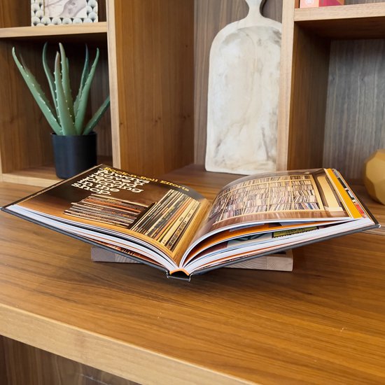 Open boek met platenhoezen op houten boekenstandaard, op een houten plank.