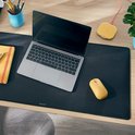 Donkergrijze bureauonderlegger met laptop, gele muis en draadloze oplader.