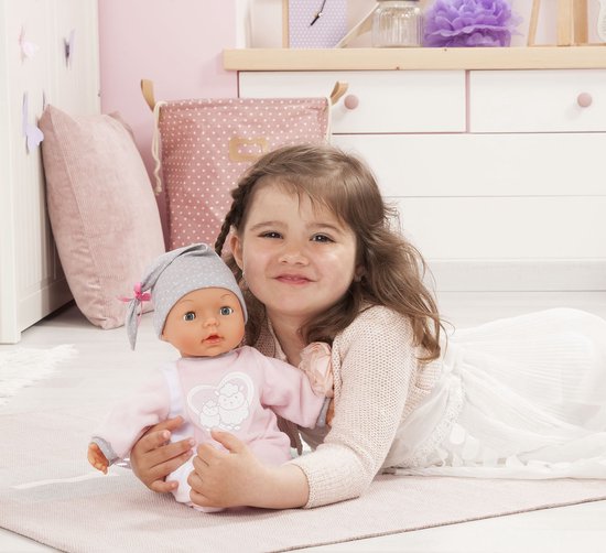 Meisje met babypop in roze slaappakje en grijze muts.