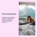 Vrouw op een bed in een camper met uitzicht op een bergmeer.