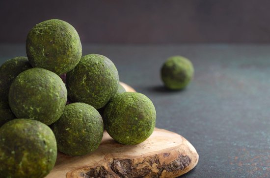 Groene matcha ballen op een houten plankje.
