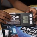 Een kind dat een Monopoly bankkaart gebruikt met de elektronische bankeenheid.