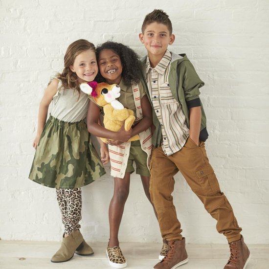 Drie kinderen die lachen, omhelzen een zacht speelgoed kangoeroe met een strik.