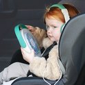 Een meisje met rood haar zit in een autostoel, draagt een koptelefoon en houdt de TIMIO speler vast met een afbeelding van een sneeuwpop.