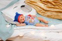 BABY born pop liggend op bed. Draagt blauwe muts met oortjes en romper met beerprint.