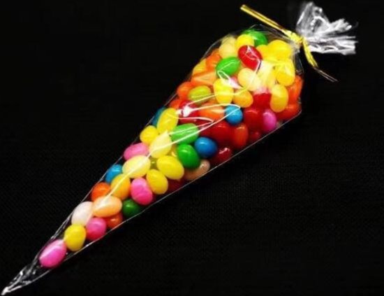 Een doorzichtige puntzak gevuld met kleurrijke jelly beans, afgebonden met een gouden touwtje.