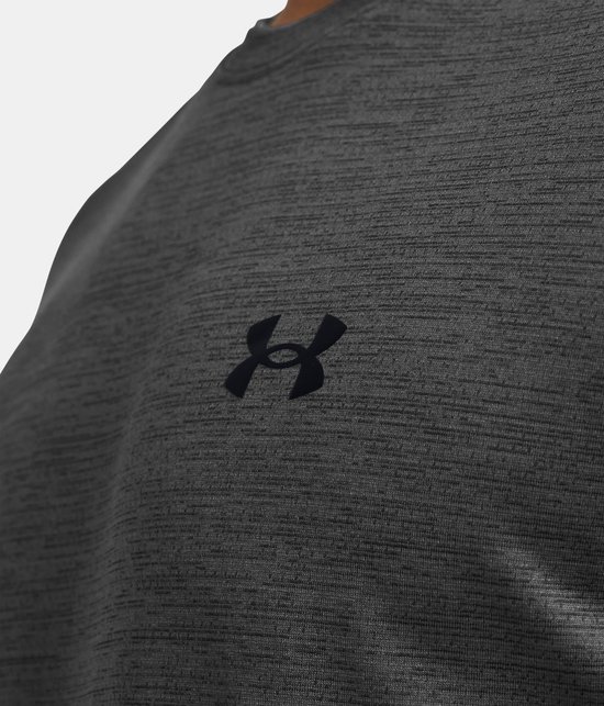 Detailopname van een grijs gemêleerd sportshirt met een zwart Under Armour logo op de borst.