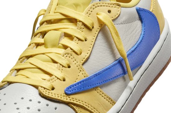 Close-up van de gele en crème Jordan 1 Low sneaker met blauwe swoosh.