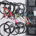 Vijf mountainbikes met kleurrijke frames hangen aan een zwart ophangsysteem.