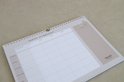Weekplanner met pastelroze en beige tinten, vakjes voor namen en dagen, en notitievak.