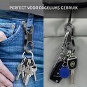 Zwarte dubbelzijdige karabijnhaak sleutelhouder met sleutelbos, gedragen aan een spijkerbroek en aan een tas.