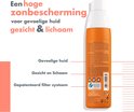 Achterkant van oranje Avène spuitfles met teksten over bescherming voor gezicht en lichaam.