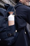 Dopper Insulated drinkfles in pebble peach en wit, in een navy rugzakvak.