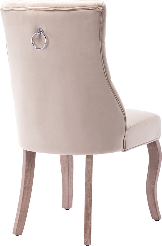 Achterkant beige fluwelen eetkamerstoel met knopquilting en een metalen ring op de rug. Houten poten.