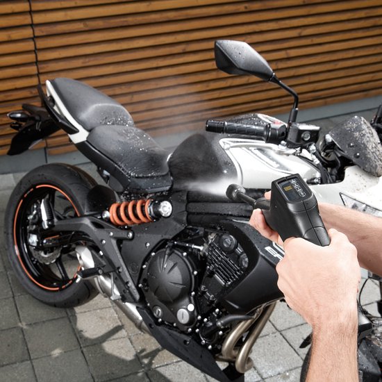 Hand met hogedrukreiniger spuitend op een motorfiets.