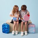 Enfants avec des boîtes à lunch; fille avec boîte bleue, garçon avec boîte rose. Sacs à lunch bleus et pastel à côté.