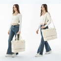 Model met crèmekleurige weekendtas in de hand en over de schouder gedragen.