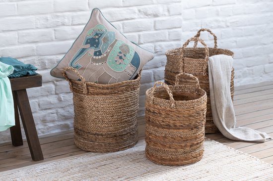 Een woonkamer met manden, een kussen met olifant, een plaid en een houten kruk.