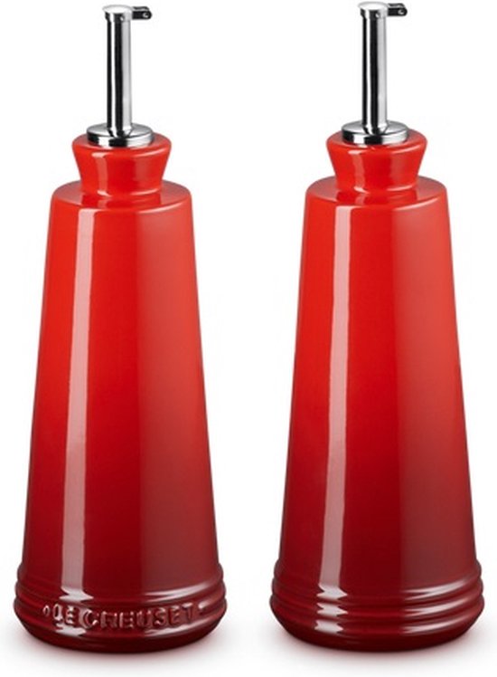 Twee kersenrode Le Creuset olie- en azijnflessen van keramiek, met zilverkleurige schenktuiten.