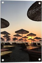 WallClassics - Tuinposter – Strand met Ligbedden en Rieten Parasols - 40x60 cm Foto op Tuinposter (wanddecoratie voor buiten en binnen)