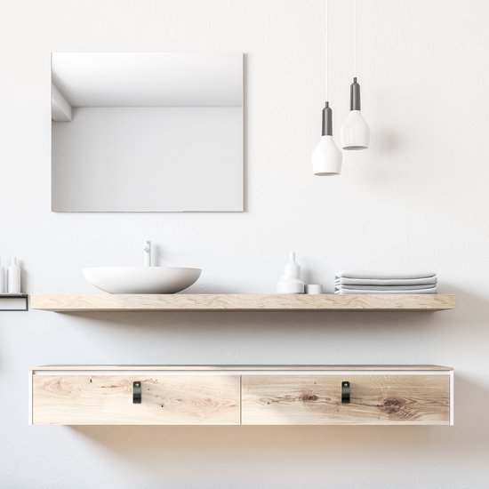 Een houten badmeubel met twee lades, voorzien van zwarte leren handgrepen, onder een wastafel met spiegel.