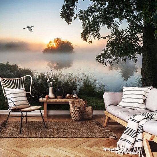 Salon décoré d'une fresque d'un lever de soleil sur un lac brumeux, avec un oiseau, une chaise, un canapé et des paniers.