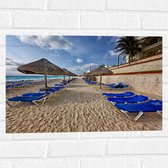 WallClassics - Muursticker - Blauwe Ligbedden op Strand met Rieten Parasols - 60x40 cm Foto op Muursticker