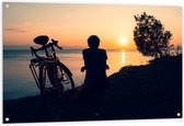 Tuinposter – Silhouet van Rustende Fietser met Fiets aan het Water bij Zonsondergang - 120x80 cm Foto op Tuinposter (wanddecoratie voor buiten en binnen)