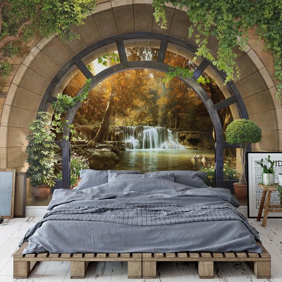 Une chambre avec un grand lit et une tapisserie de cascade d'automne vue par une fenêtre. La pièce est décorée de plantes.