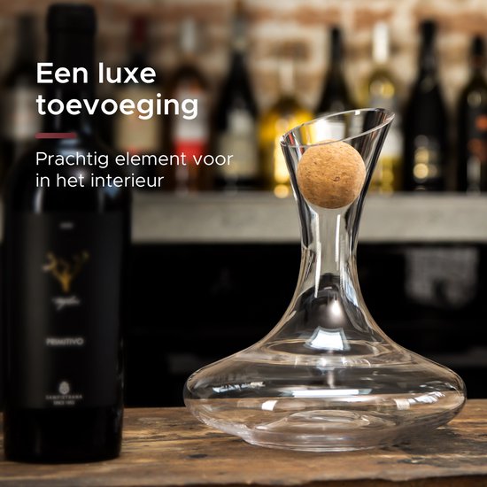 Carafe à vin transparente avec bouchon en liège dans le bec, à côté d'une bouteille de vin rouge.