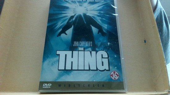 DVD hoes van John Carpenter's The Thing met een silhouet van een mens met een stralende lichtkegel uit het hoofd.