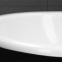 Détail du bord d'un lavabo ovale blanc sur un fond de carrelage sombre.