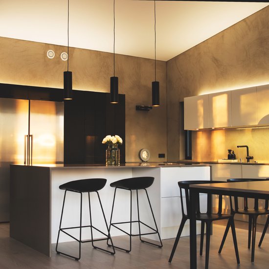 Moderne keuken met verlichting, roestvrijstalen koelkast, kookeiland met barkrukken en een eettafel.