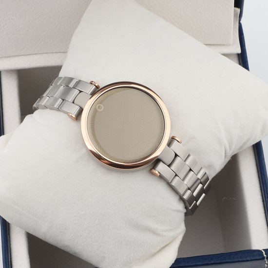 Bracelet de montre connectée en métal argenté avec des accents en or rose, sur un coussin blanc.