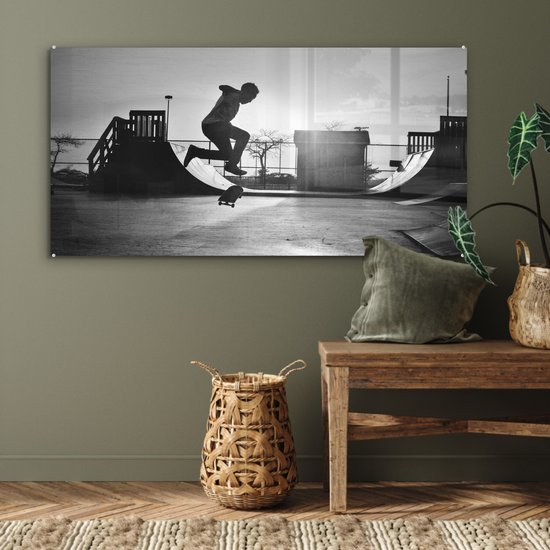 Peinture sur verre MuchoWow® - Un garçon fait une cascade avec son skateboard pendant le coucher du soleil - noir et blanc - 120x60 cm - Peintures sur verre acrylique - Photo sur Glas
