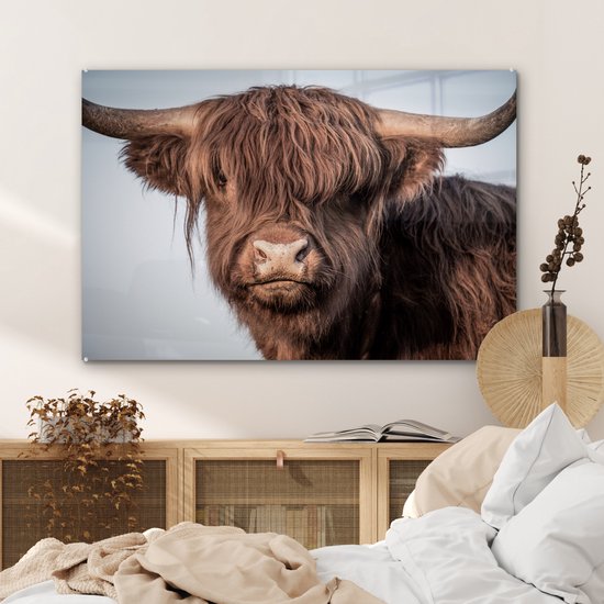 Glasafbeelding van een bruine Schotse hooglander met grote hoorns, hangend boven een bed.