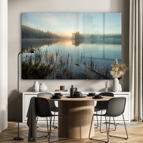 Une peinture sur verre d'un lever de soleil sur un lac brumeux, dans une salle à manger avec une table ronde et des chaises.