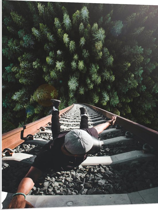 PVC Schuimplaat- Man Hangend aan Spoor boven de Bomen - 75x100 cm Foto op PVC Schuimplaat