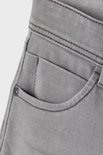 Grijze jeans met een kleine zak en een metalen knoop.