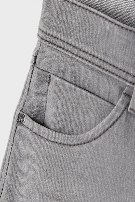 Grijze jeans met een kleine zak en een metalen knoop.