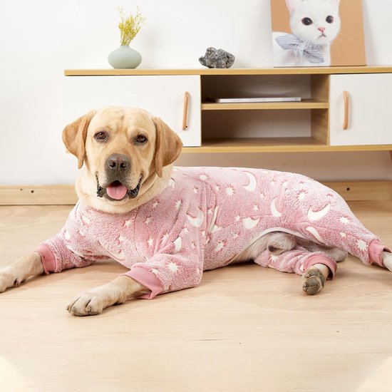 Labrador in roze hondenpyjama met maan- en sterrenprint, ligt op de grond.