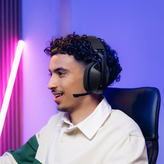 Een jonge man met een pet en groene/witte trui draagt een zwarte Logitech G gaming headset.