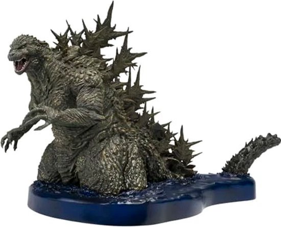 Grijze Godzilla figuur met scherpe rugplaten, knielend op een blauwe waterbasis.