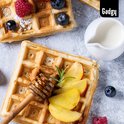 Gouden Brusselse wafel met gesneden perzik, honing en munt, naast een kannetje melk.