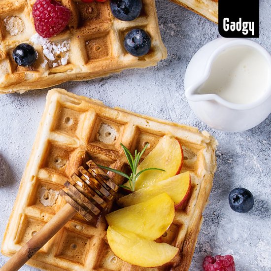 Gouden Brusselse wafel met gesneden perzik, honing en munt, naast een kannetje melk.