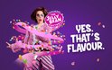 Vrouw met roze bontjas en gestreepte broek, omringd door een roze lint en veelkleurige jelly beans. "YES. THAT'S FLAVOUR."