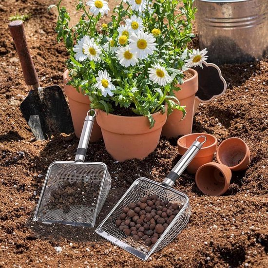 Twee roestvrijstalen zeefscheppen in de aarde, met bloeiende planten en tuingereedschap.