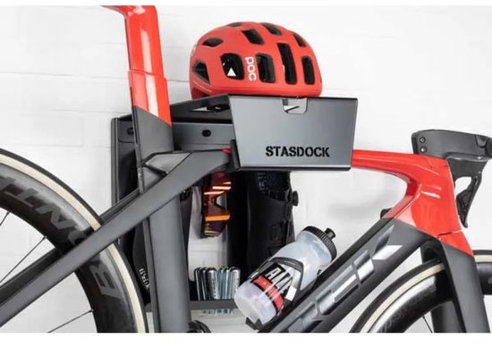 Zwarte en rode racefiets met rode helm en bidon op een Stasdock muurbeugel.